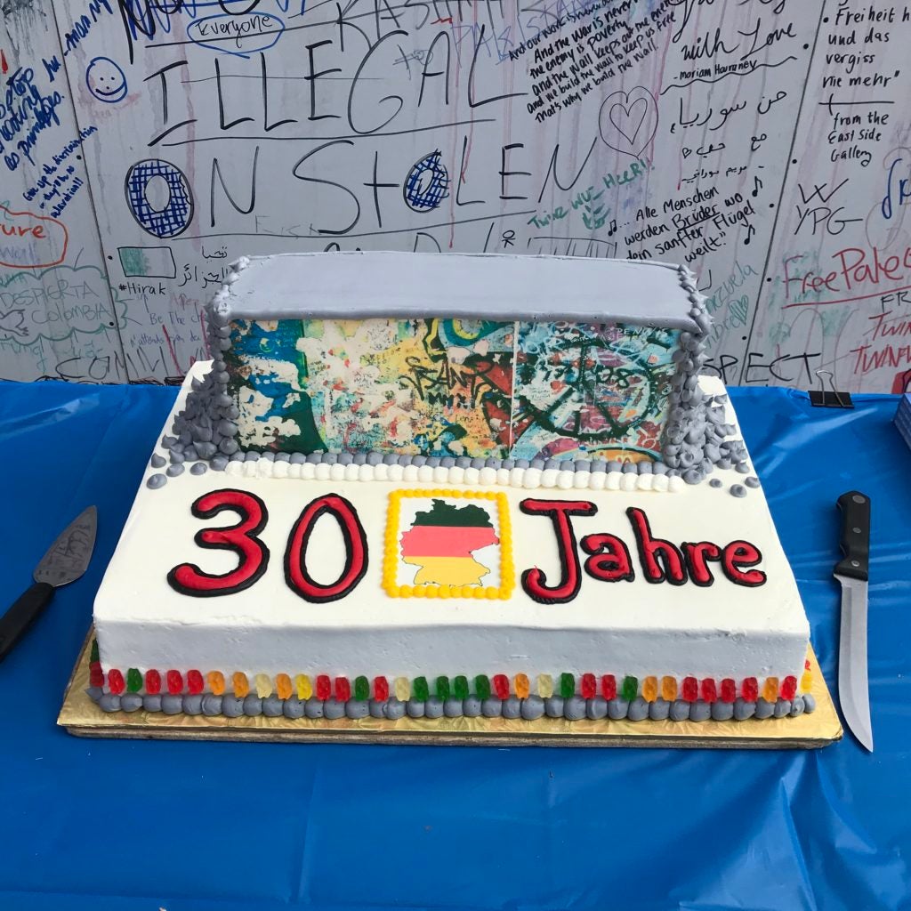 Berlin Wall cake in front of the replica Berlin Wall built on Georgetown University's campus