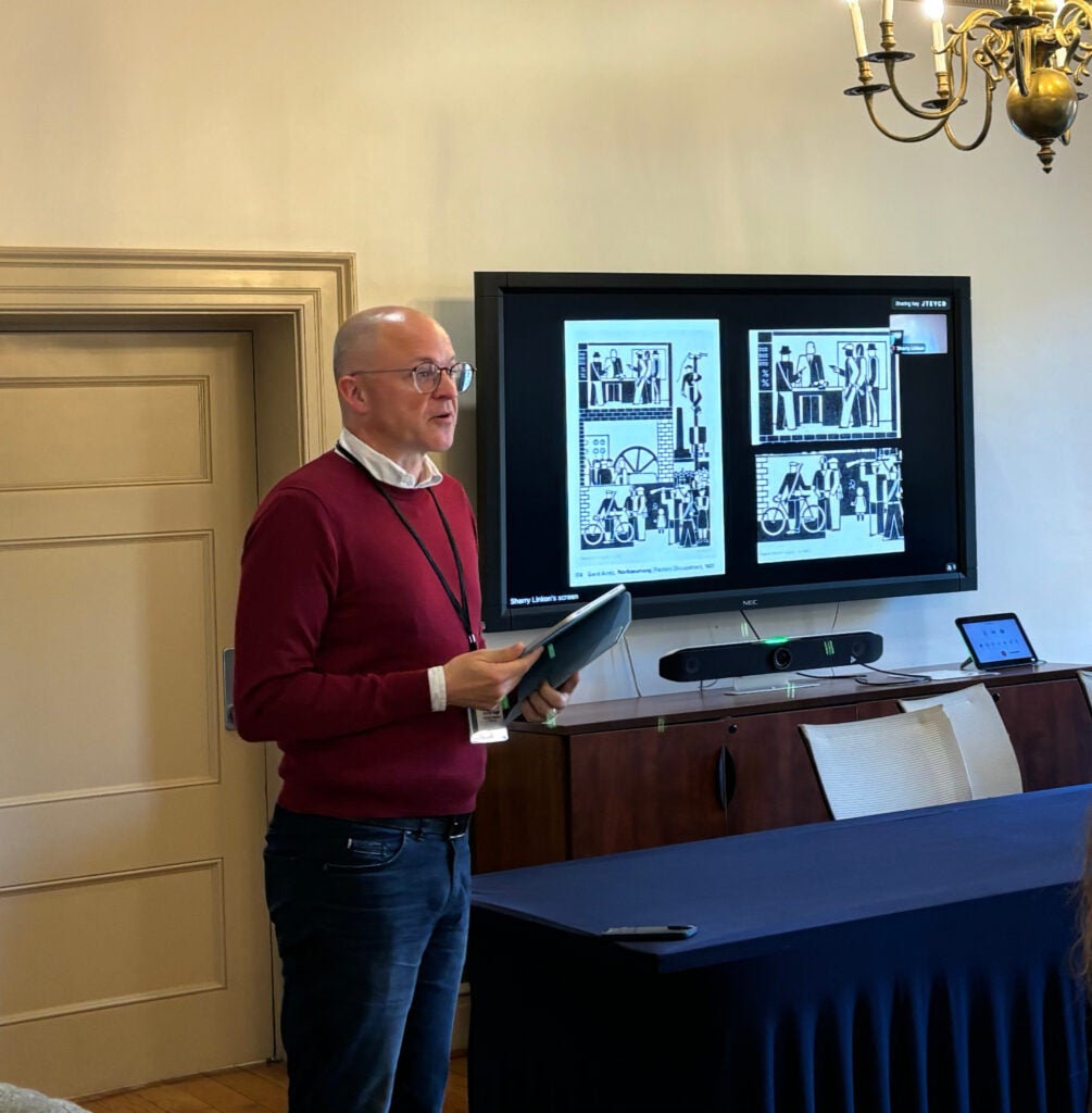 Prof. Steffen Siegel stands next to a table during his keynote presentation