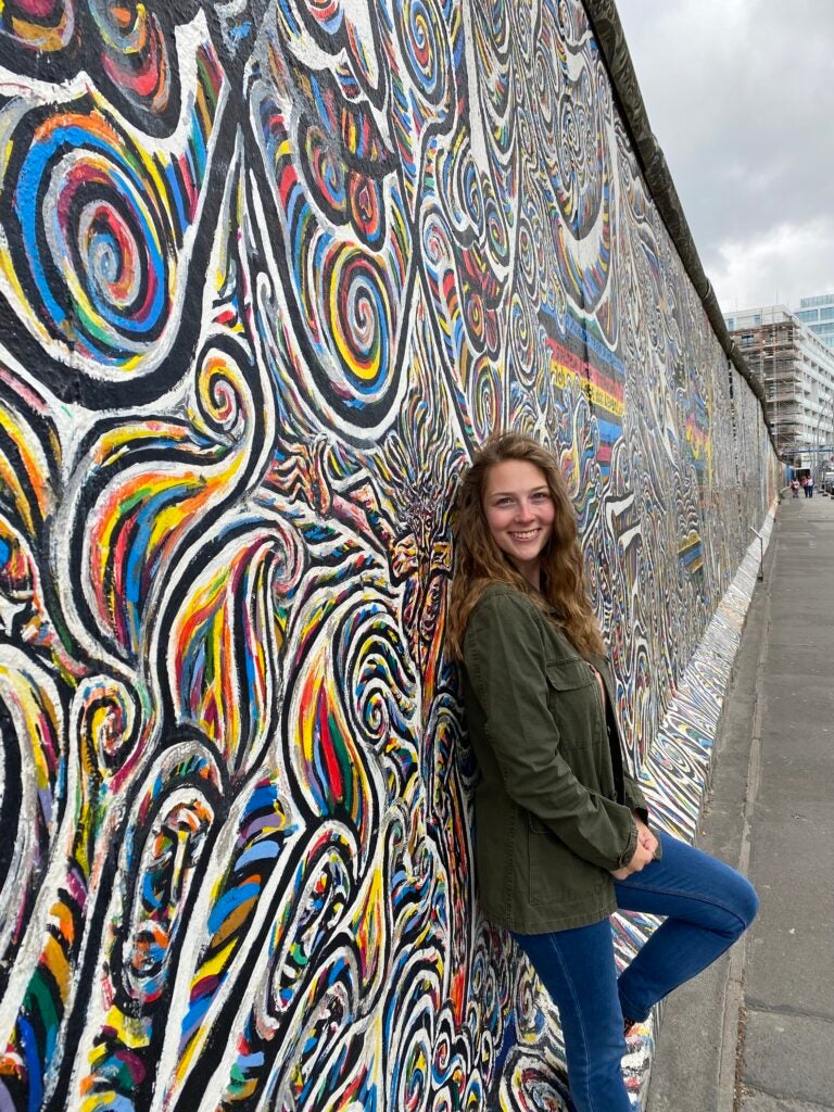 Katie Miller-Purrenhage leans against a piece of the Berlin Wall